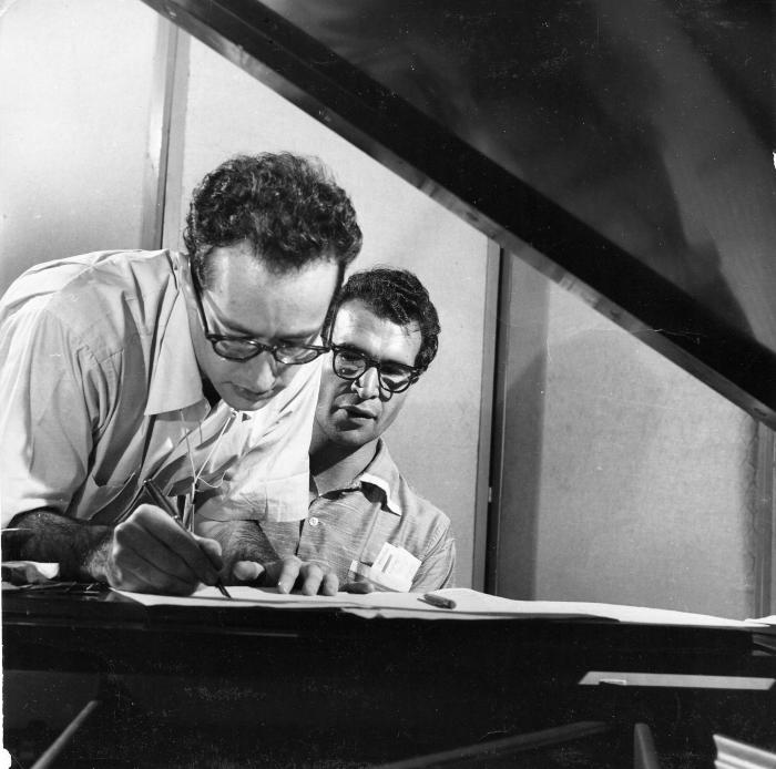 Dave Brubeck at piano, Paul Desmond standing at piano writing