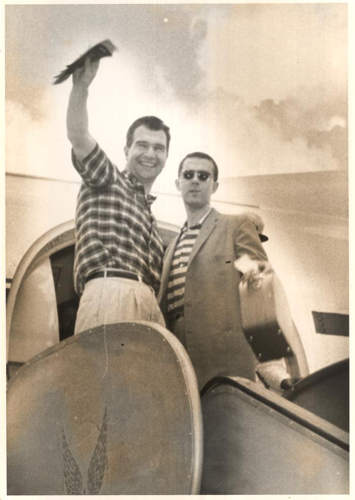 Dave Brubeck (waving), Joe Morello standing in front of the open hatch of an airplane (India)