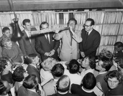 Dave Brubeck blowing on a didjeridoo; Paul Desmond looks on with amusement (Brash's Music Store, Melbourne, Australia)