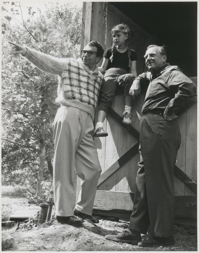 Dave Brubeck pointing to something in the distance, Walter Cronkite, and Catherine Brubeck (perched on the barn door) during filming of an episode of the CBS television show "The 20th Century" at Dave Brubeck's home (Wilton, Connecticut)